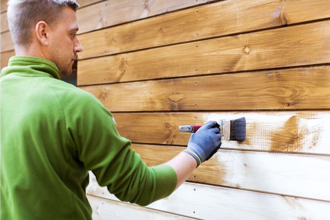 Decorator painting wooden exterior of house.