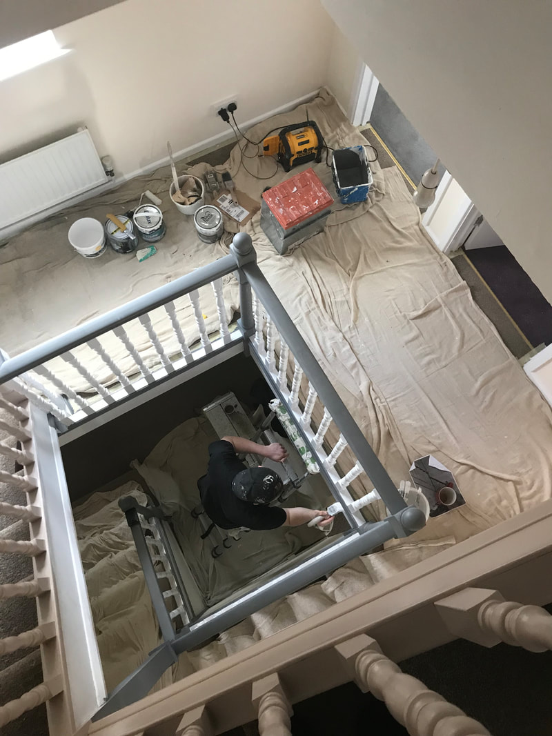A decorator is painting a staircase grey and white.